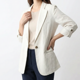 Veste blazer en lin blanche Olyndra London, coupe élégante et légère, portée sur un fond neutre.